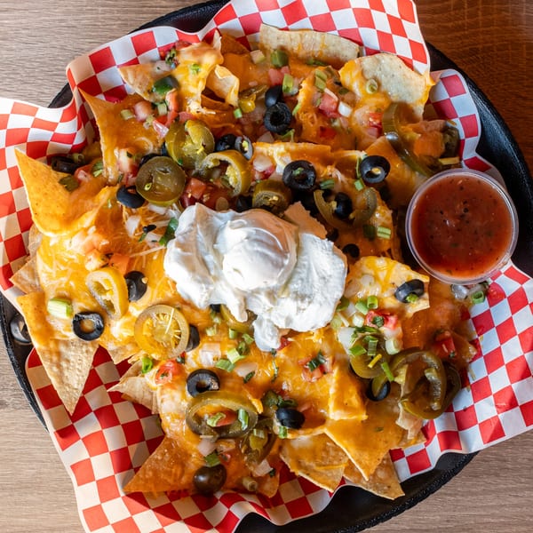 A platter of Republic's nachos with cheese, jalapeños, olives, sour cream, and salsa.