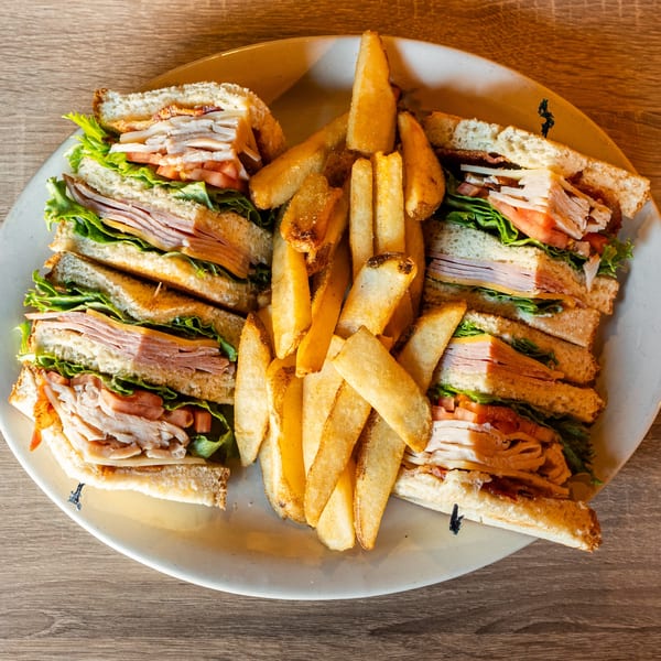 A large plate of Republic's club sandwiches, cut into quarters, served with a pile of golden fries.