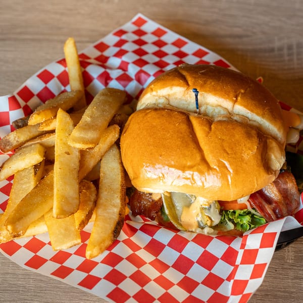 A Republic burger with bacon, mushrooms, and cheese, served with seasoned fries in a red checkered basket.