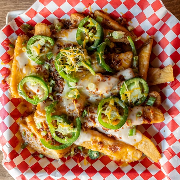 Republic's loaded fries with melted cheese, jalapeños, bacon bits, and green onions on red checkered paper.
